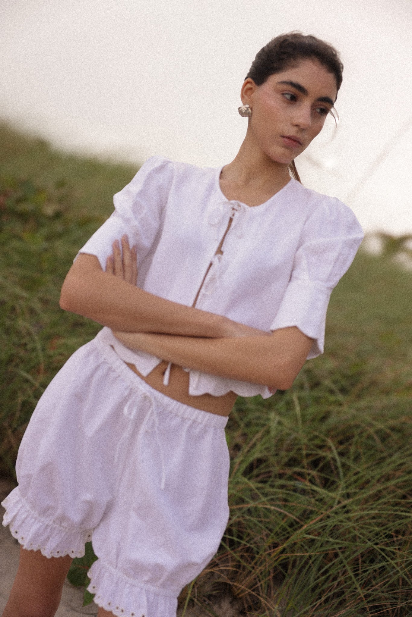 Woman wearing a white outfit with ruffled details in a natural setting