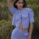 Woman wearing a blue checkered outfit standing in a natural setting