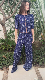 Woman modeling a blue printed linen set with matching top and pants in an outdoor setting